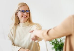Frau reicht einer anderen Person die Hand als Zeichen von Vertrauen und wertschätzender Kommunikation.